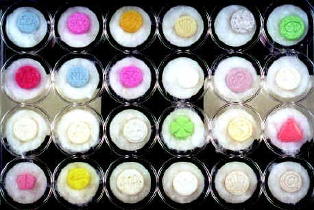 Numerous pills in various colors and shapes stamped with different logos